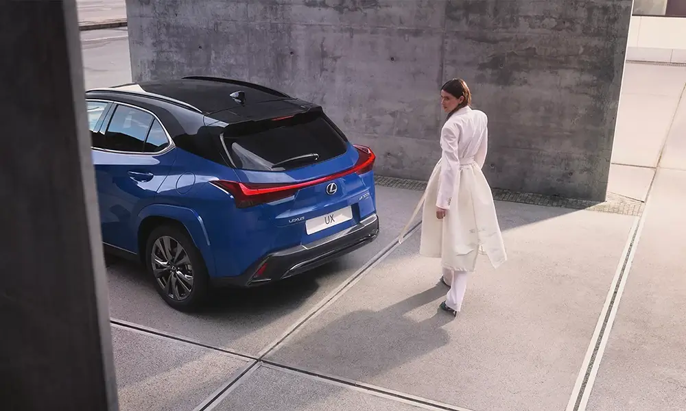 Egy Lexus UX mellett sétáló nő