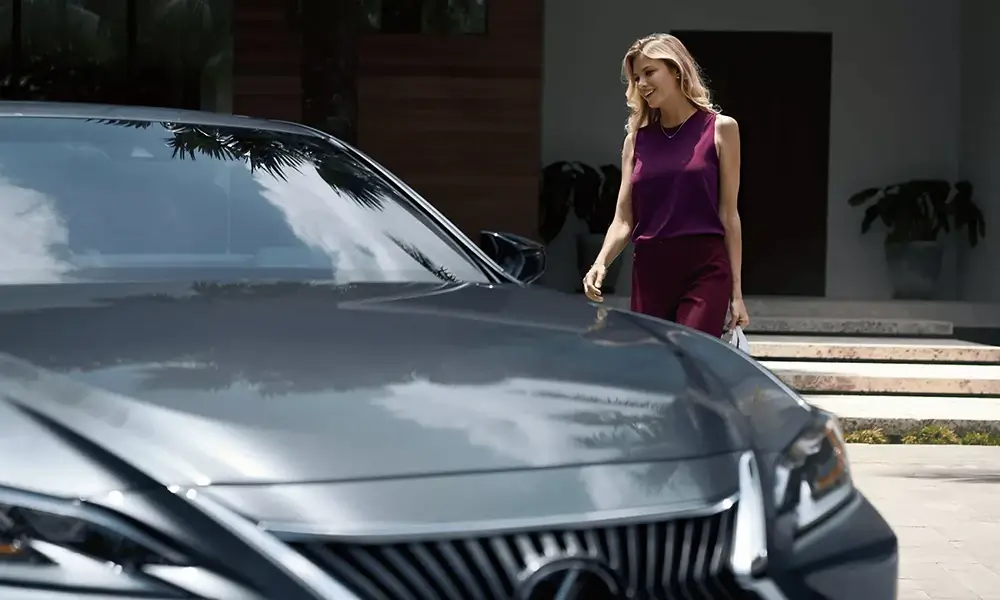 Egy szürke Lexushoz közeledő nő.